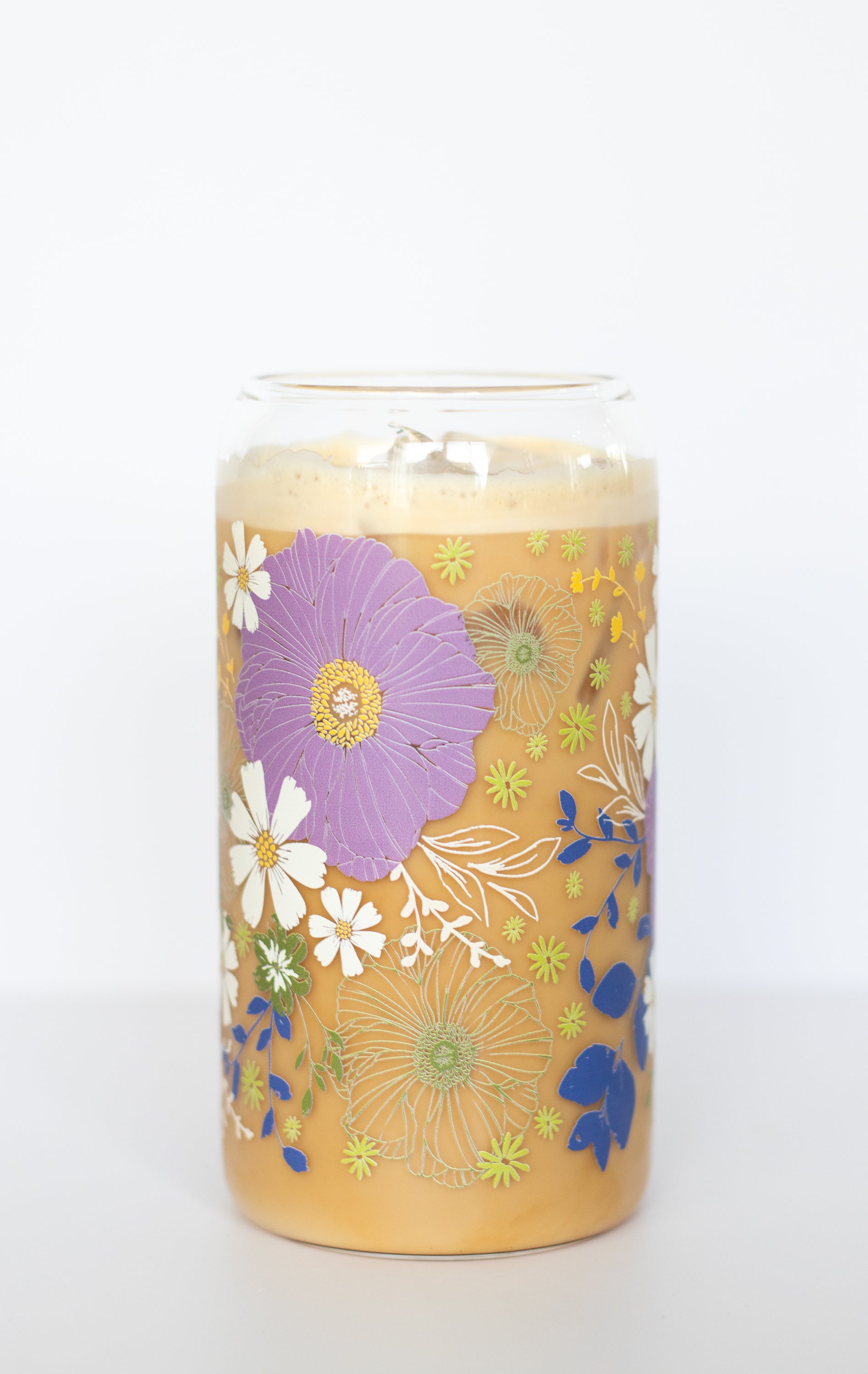 A can glass with a purple anemone and white daisy floral design on a white background.