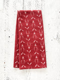 A red waffle-weave kitchen tea towel with a white hand-drawn longhorn cow skull pattern, folded lengthwise in half, on a textured white background.