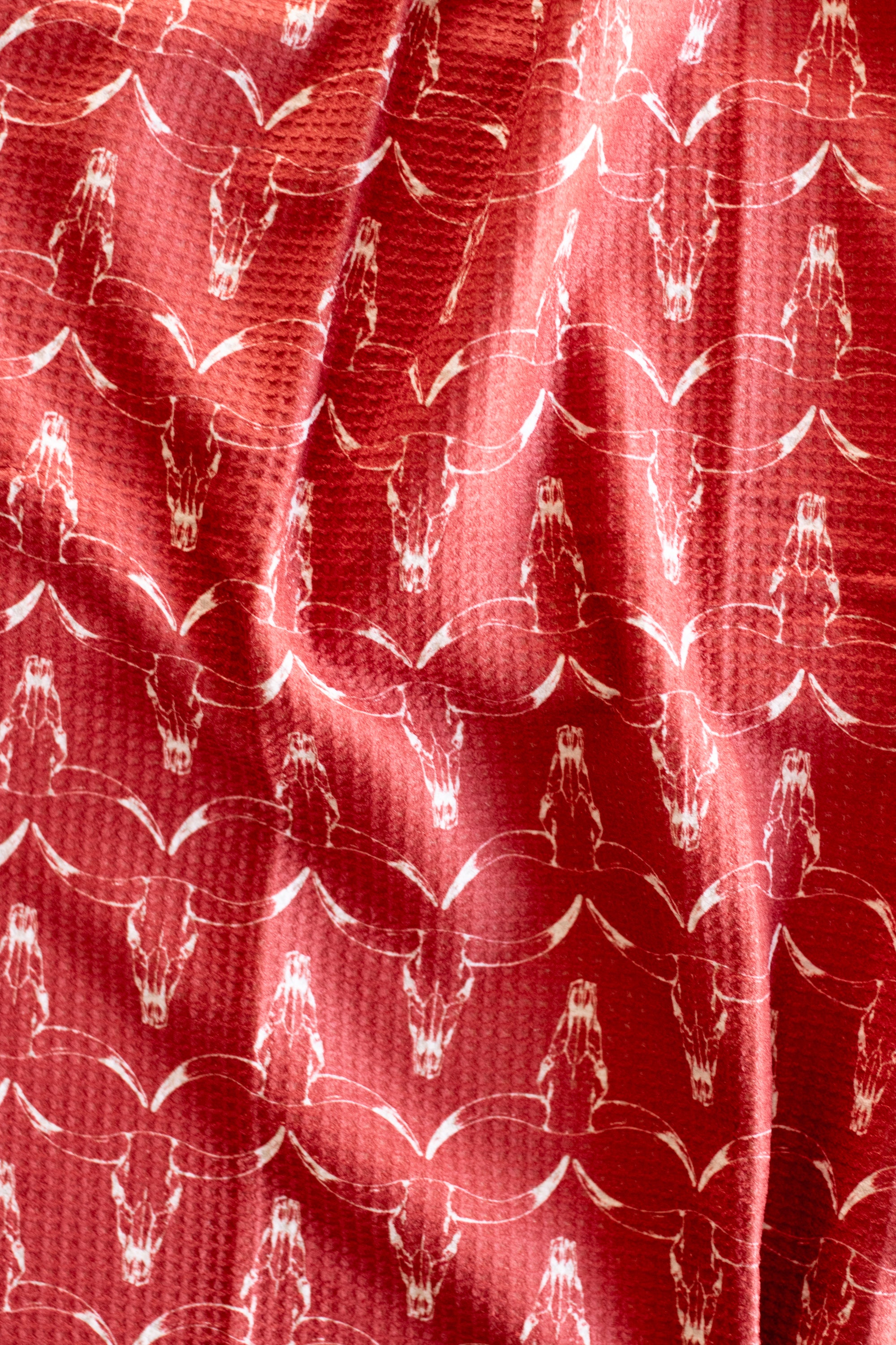 Rich red waffle-weave kitchen tea towel with a white longhorn cow skull pattern
