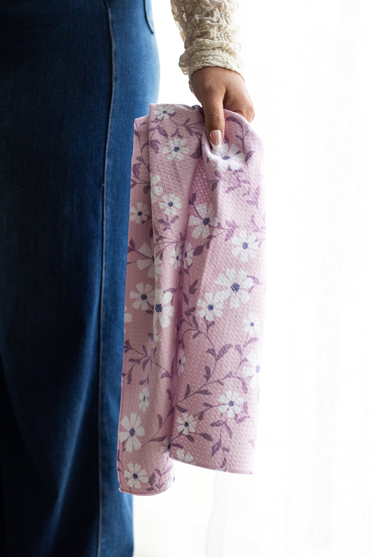 Person holding a pink floral waffle-weave kitchen tea towel against a white background.