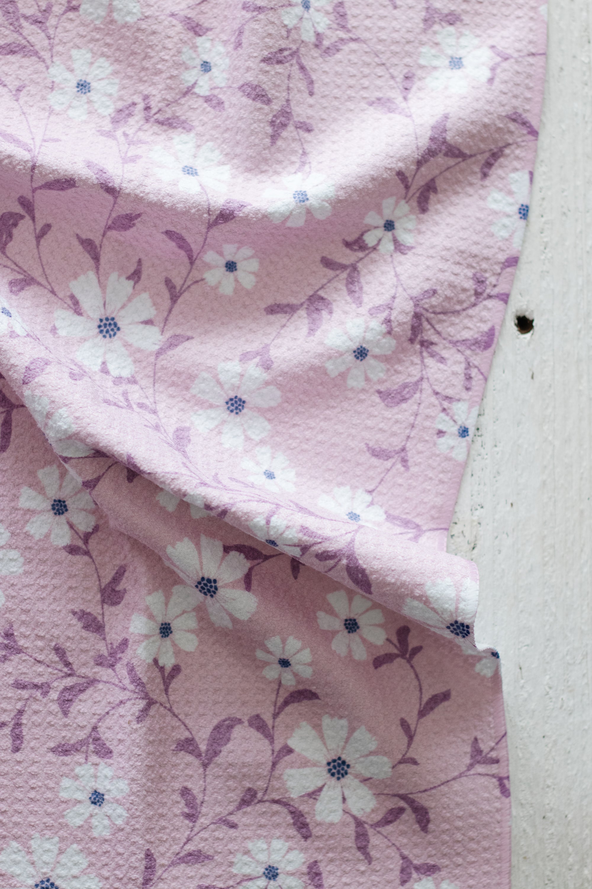 Pink floral waffle-weave kitchen tea towel  on a white background.