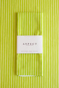 A folded kitchen tea towel with a lime green and white vertical stripe pattern, wrapped in a white paper belly band labeled 'ASPECT HOME GOODS' and 'Kitchen Tea Towel'.