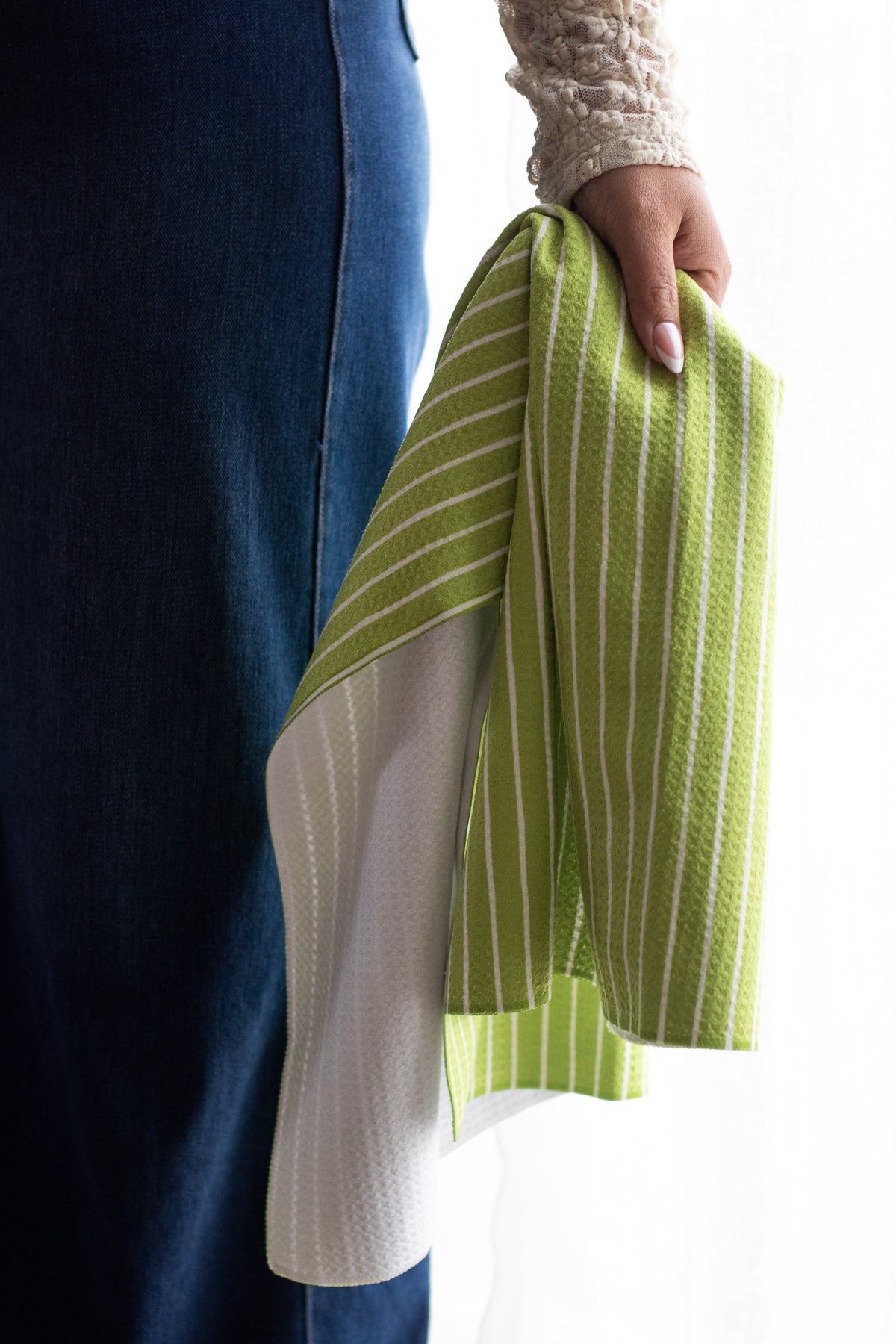 Person holding a green-and-white striped waffle-weave kitchen tea towel.