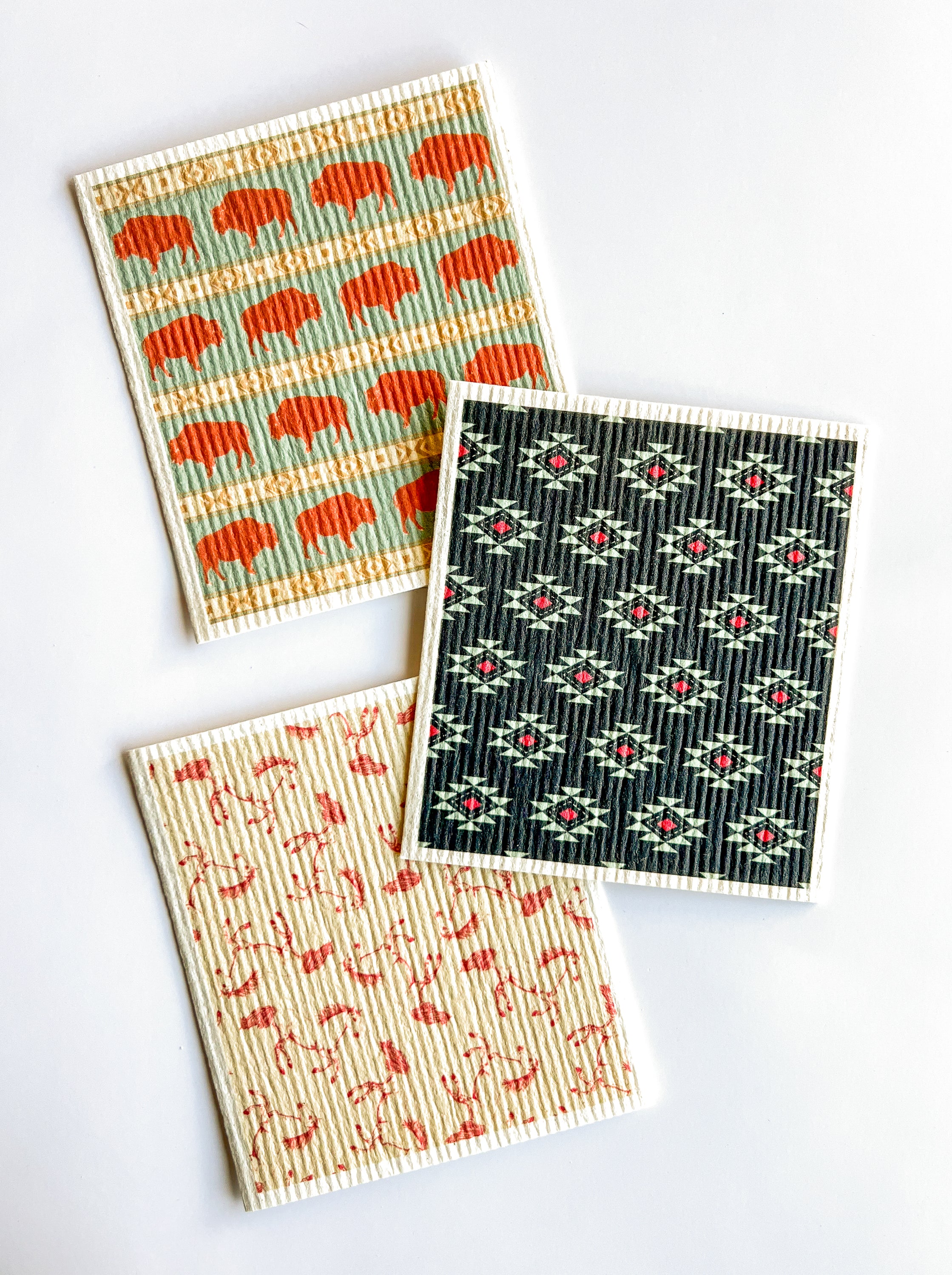 Three Western-patterned Swedish dishcloths on a white background.