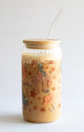 A can glass tumbler with a cowboy-themed design, bamboo lid, and a glass straw on a white background