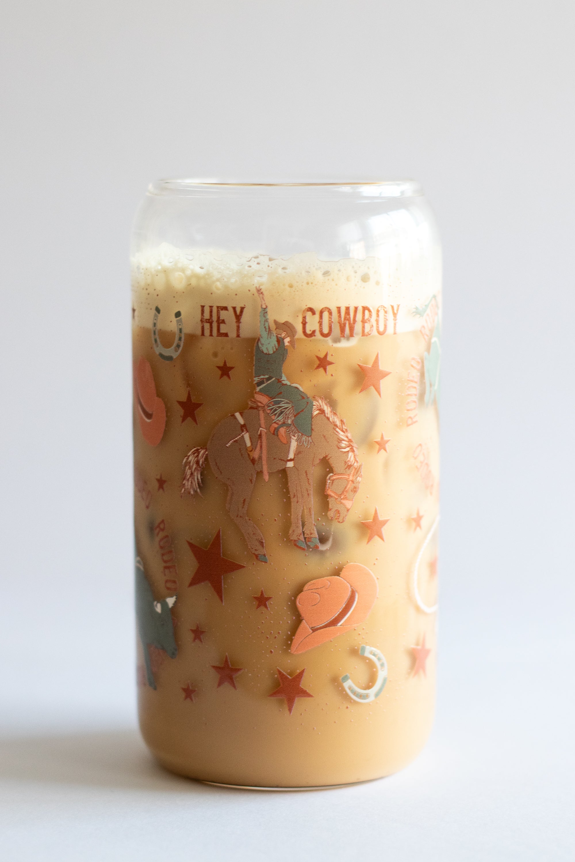 A can glass tumbler with a cowboy-themed design and text on a white background