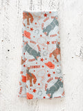 A waffle-weave kitchen tea towel with a cowboy rodeo pattern, folded lengthwise in half, on a textured white background.