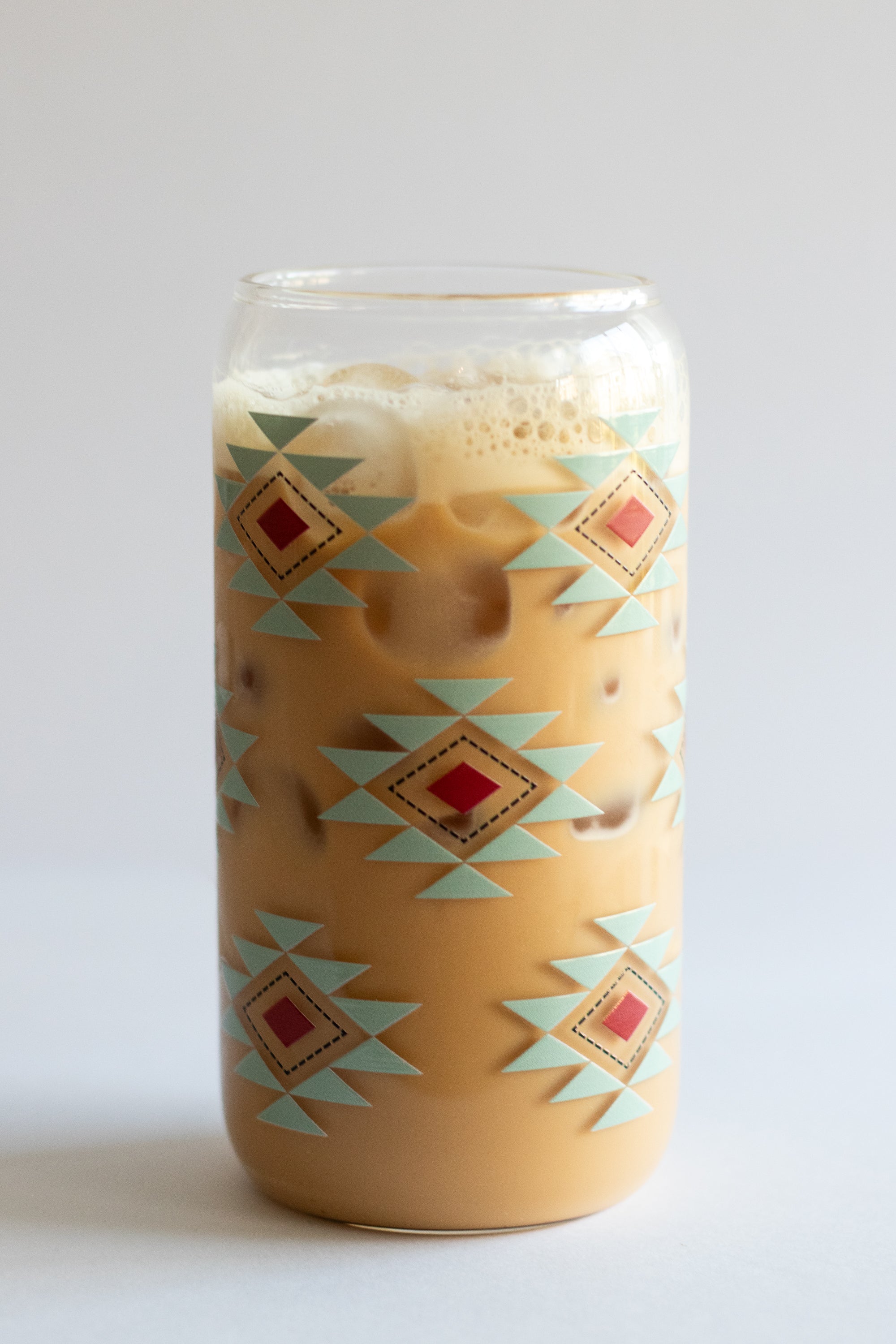 Can glass with a southwestern geometric pattern design in turquoise, red, and black, on a white background