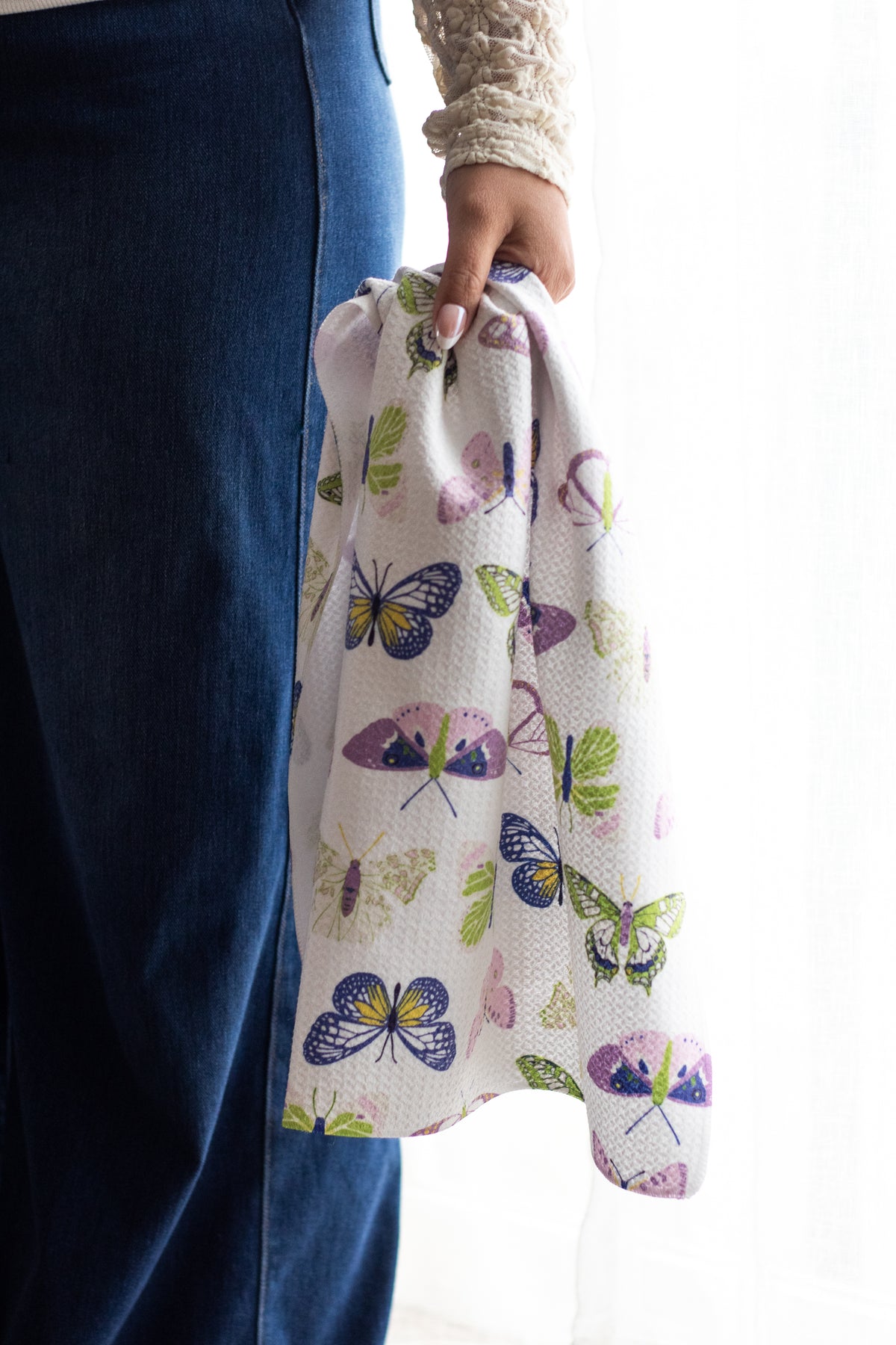 Person holding a colorful butterfly-patterned waffle-weave kitchen tea towel against a white background.